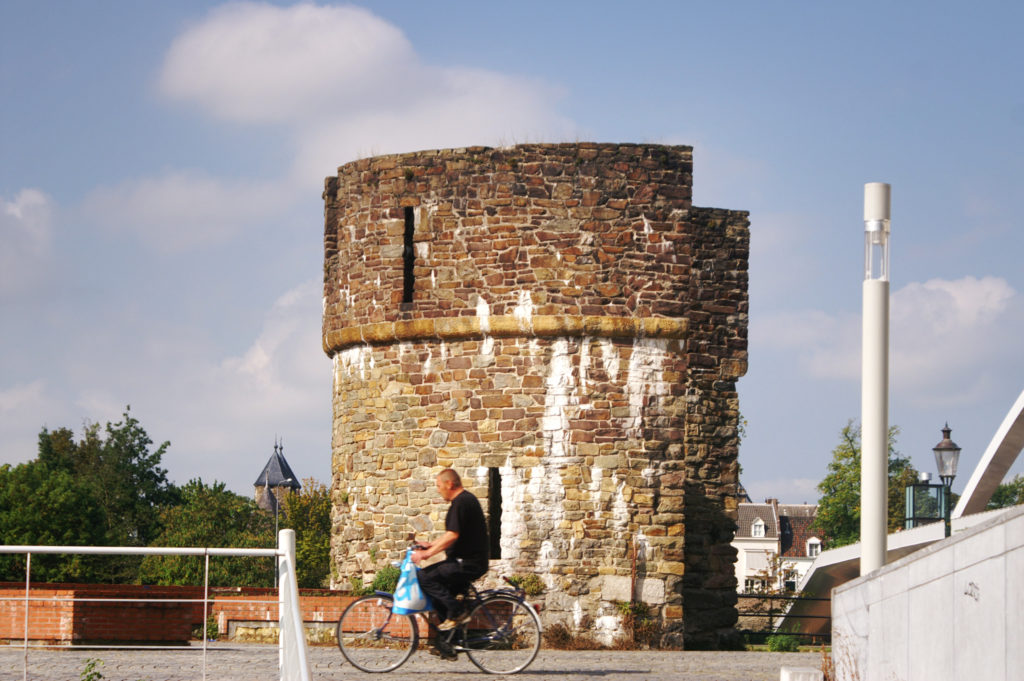 A very small tower with a man riding a bicycle in front