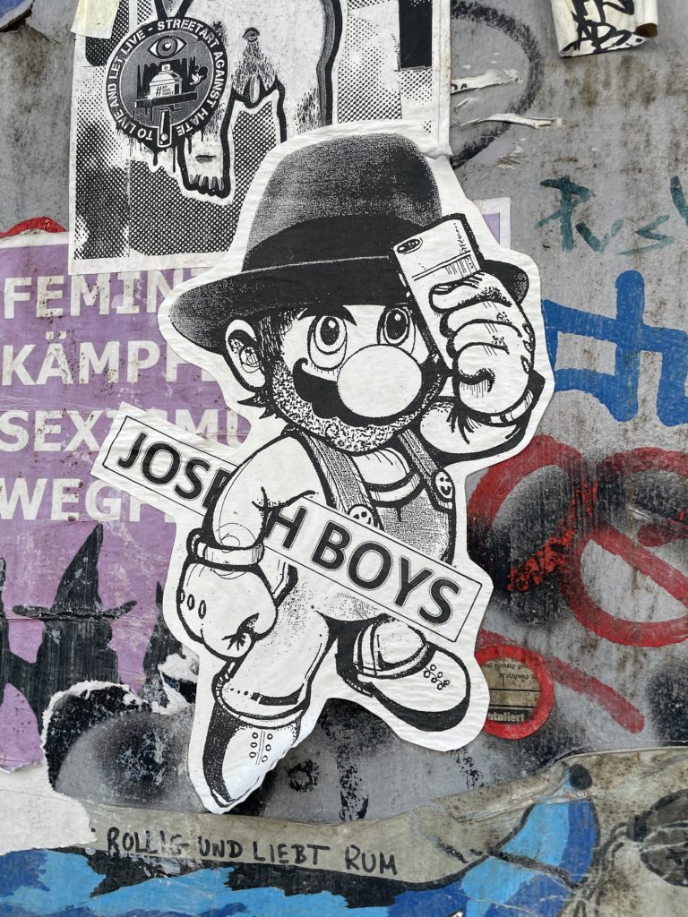 Stylized Mario holding "Joseph Boys" sign